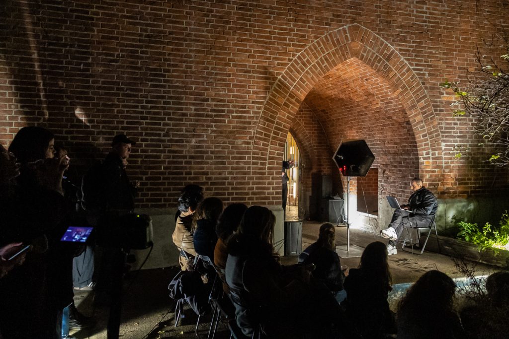 Menschen stehen im Dunkeln vor einem Backsteingebäude
