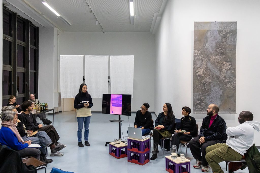 Eine Person spricht stehend zu einem sitzenden Publikum