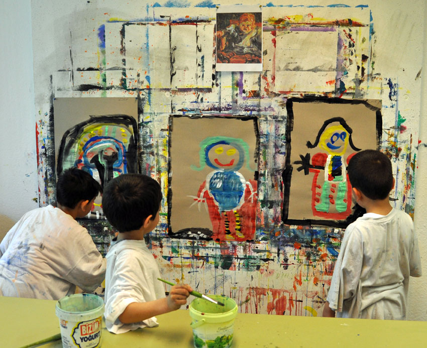 Three children in front of their paintings