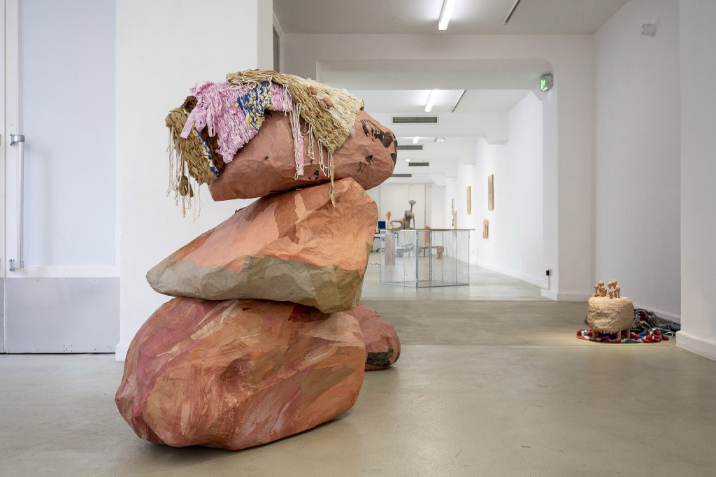 Drei pinke übereinandergestapelte Blöcke mit Stoff darauf in einem weißen Raum