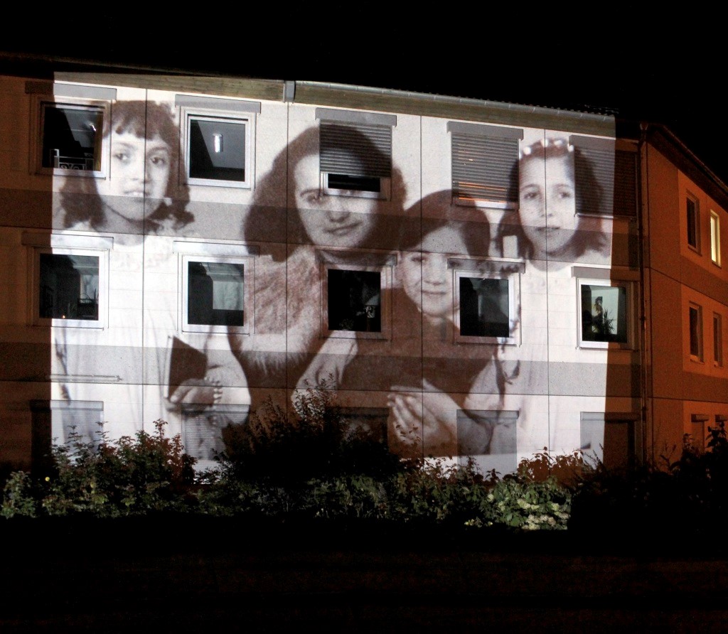 Black and white photograph of children projected onto a house wall