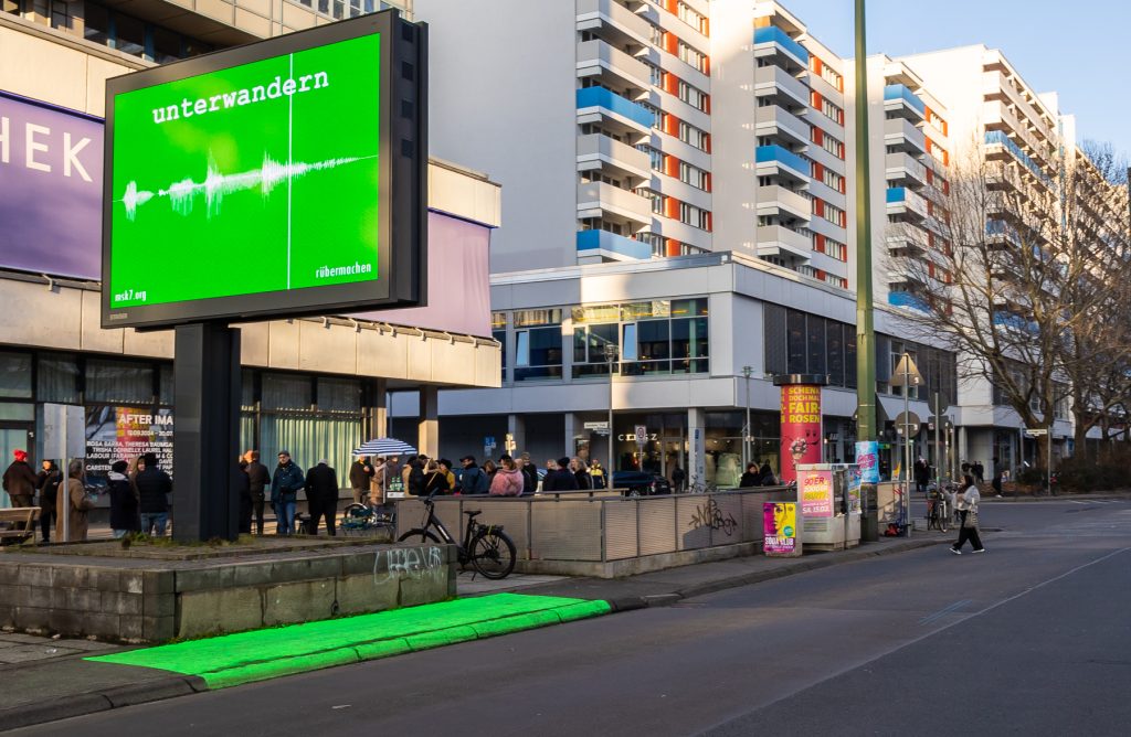 Straße in der Abendsonne mit Reklametafel mit giftgrünem Plakat, auf dem