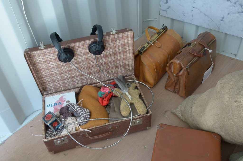 Offener Koffer mit Mütze, Teddybär und anderen Objekten darin