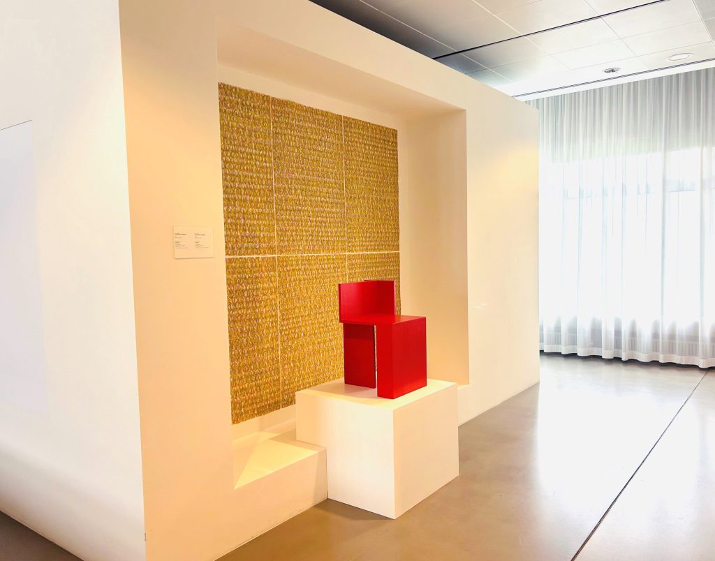 Roter Stuhl auf weißem Sockel vor goldenem Hintergrund