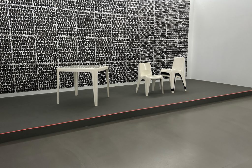 Moderne Tisch-Stuhl-Gruppe vor dunklen Quadraten an der Wand