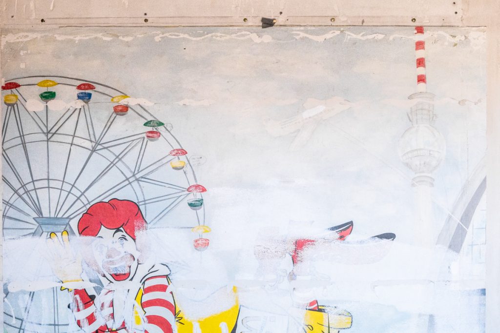 Verblichene Wandbemalung mit Clown, Riesenrad und Fernsehturm.