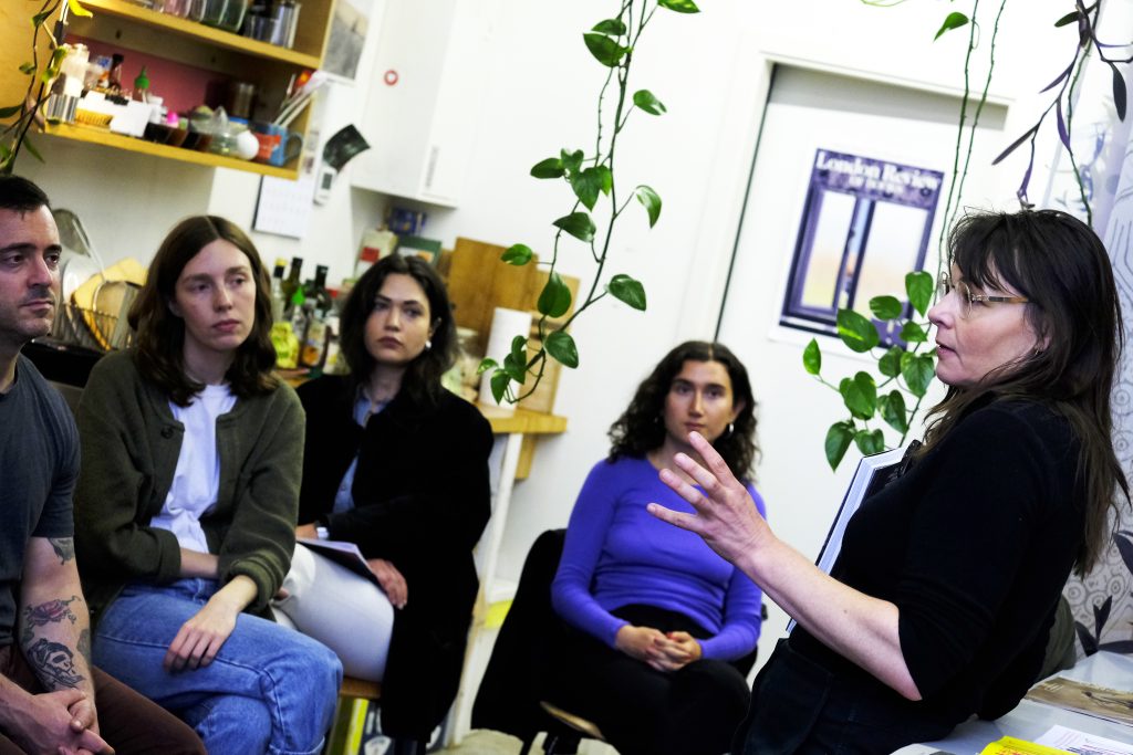 Frau erzählt vier vor ihr sitzenden Menschen etwas