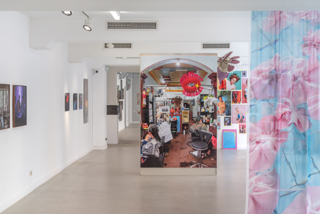 Heller Ausstellungsraum in dem eine Vielzahl an Farbfotografien zu sehen ist