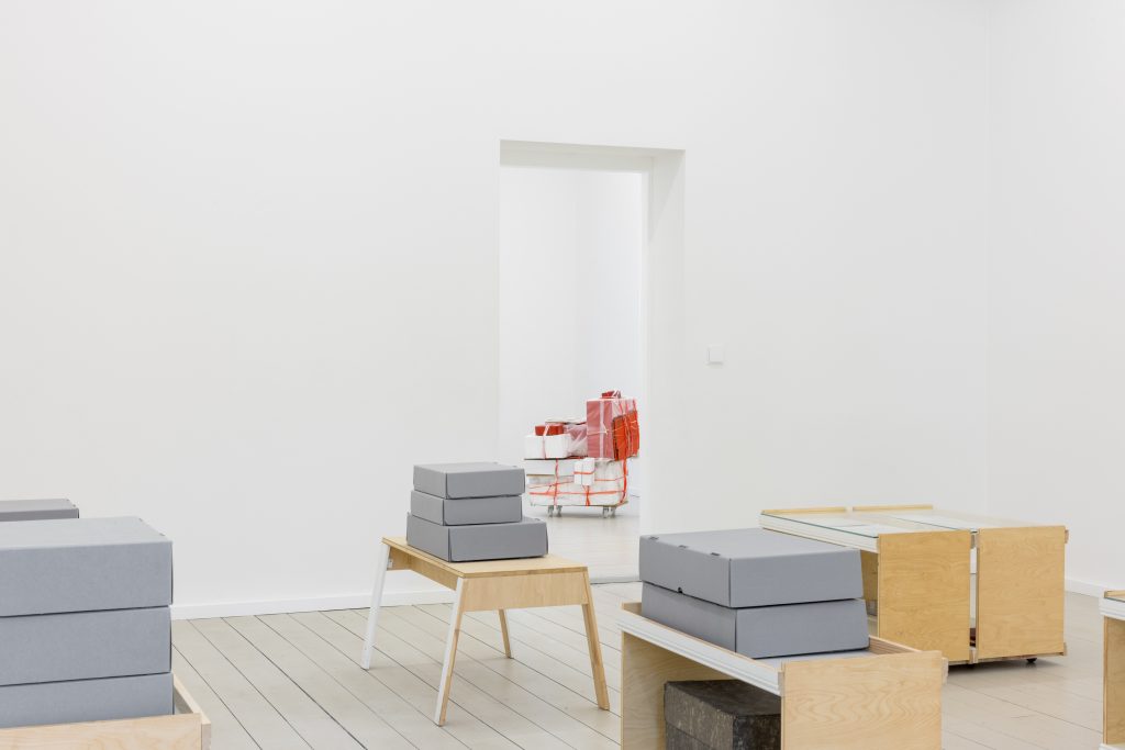 Graue Kartons auf Tischen in einem weißen Raum