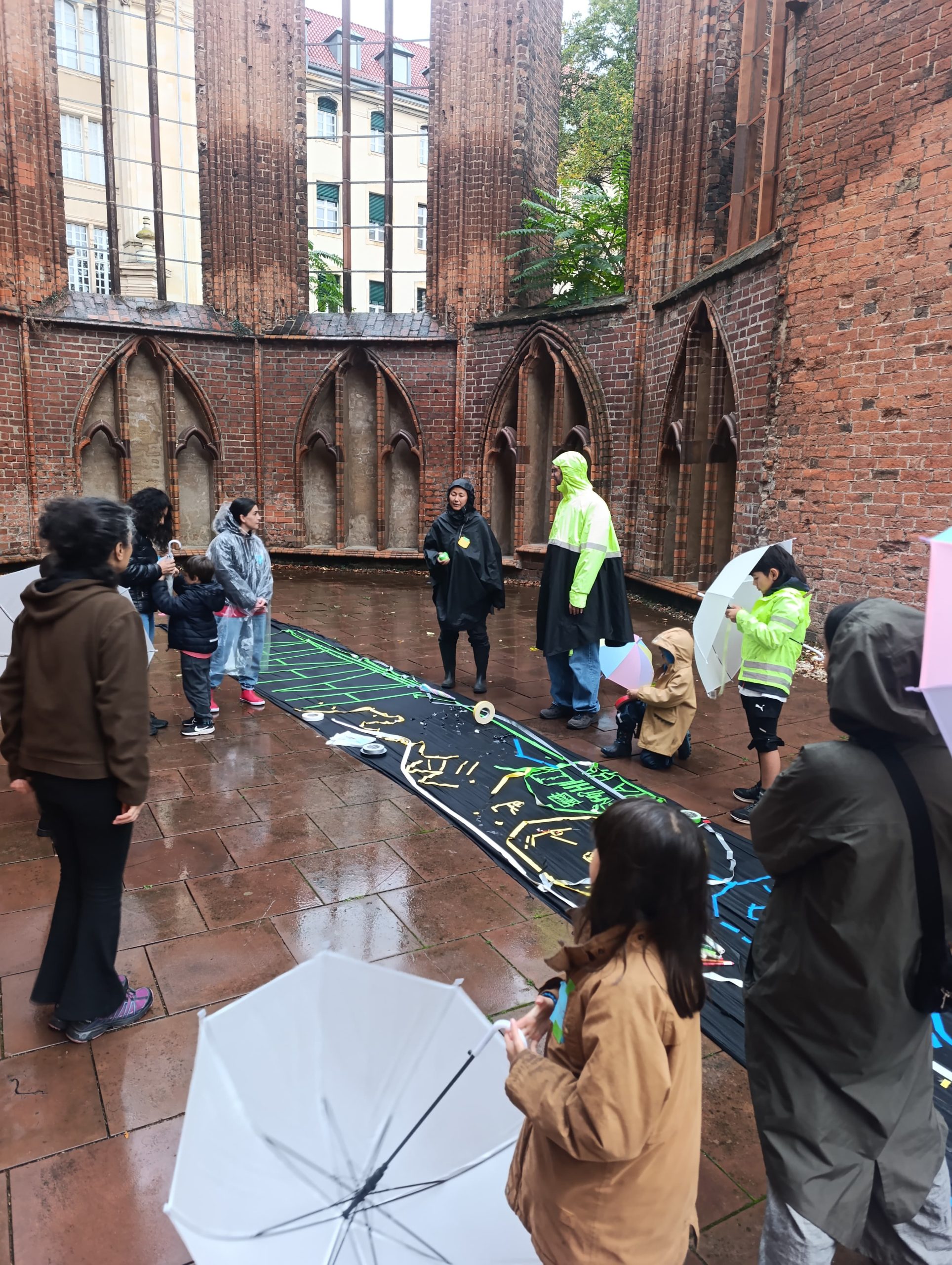 Menschen im Regen in einer Kirchenruine mit Stoffbahn in der Mitte