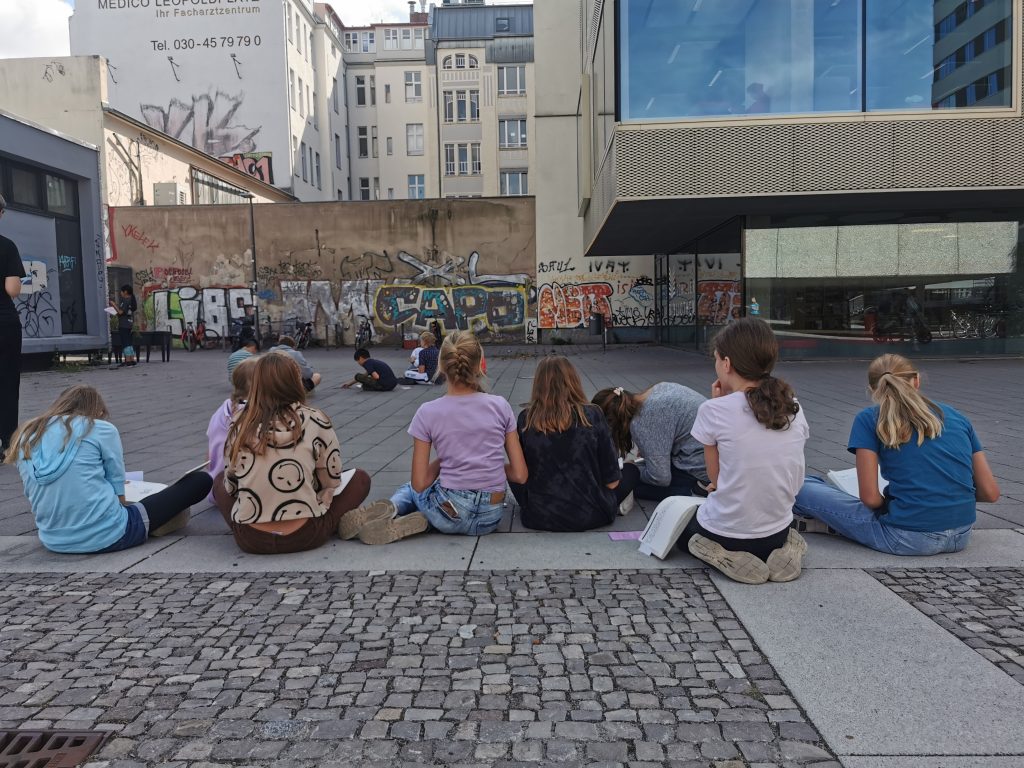 Kinder sitzen auf einem Stadtplatz