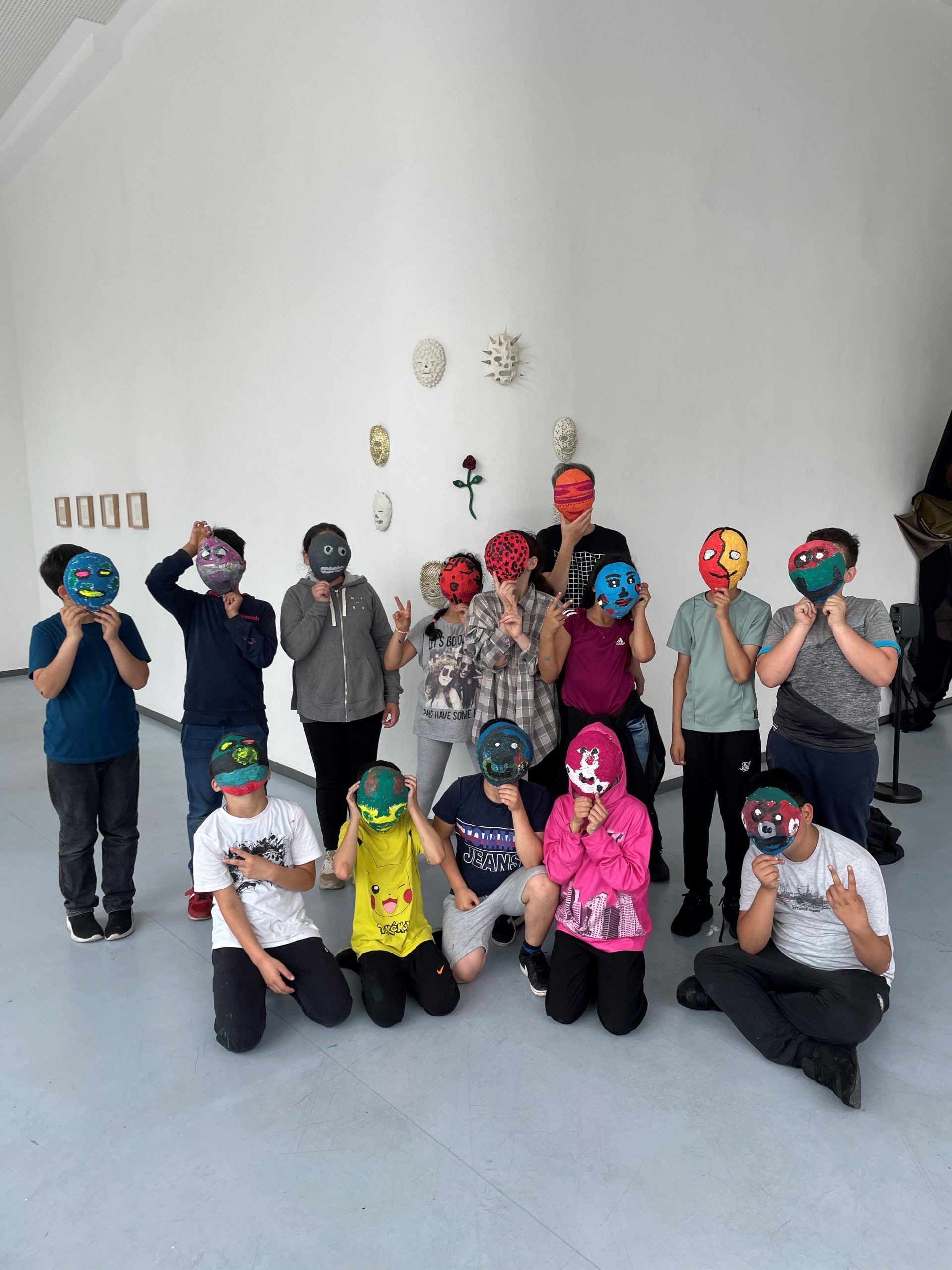 Jugendliche halten sich bunte Masken vors Gesicht