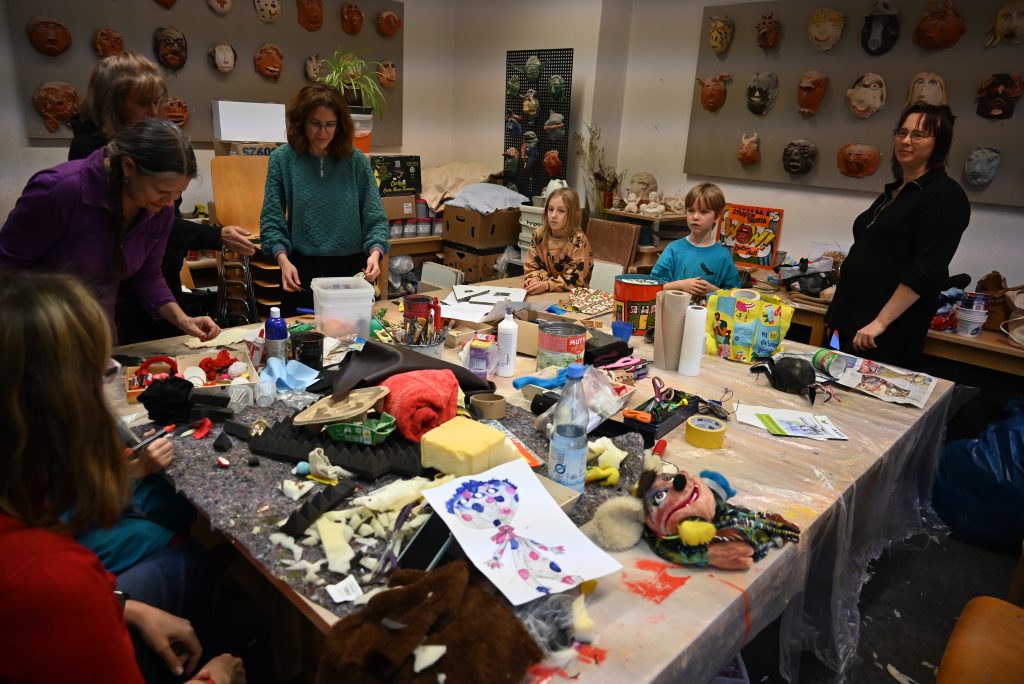 Kinder an einem mit Bastelmaterialien bedeckten Tisch