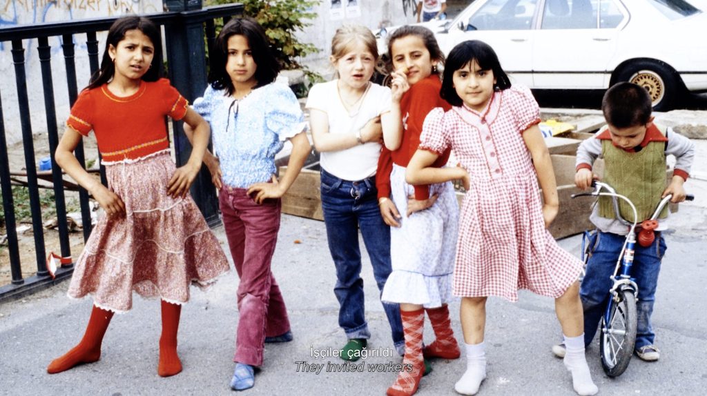 Eine Gruppe von sechs Kindern im Grundschulalter in bunter Kleidung blickt selbstbewusst in die Kamera. Der Junge rechts im Bild ist jünger als die Mädchen und sitzt auf einem Fahrrad.