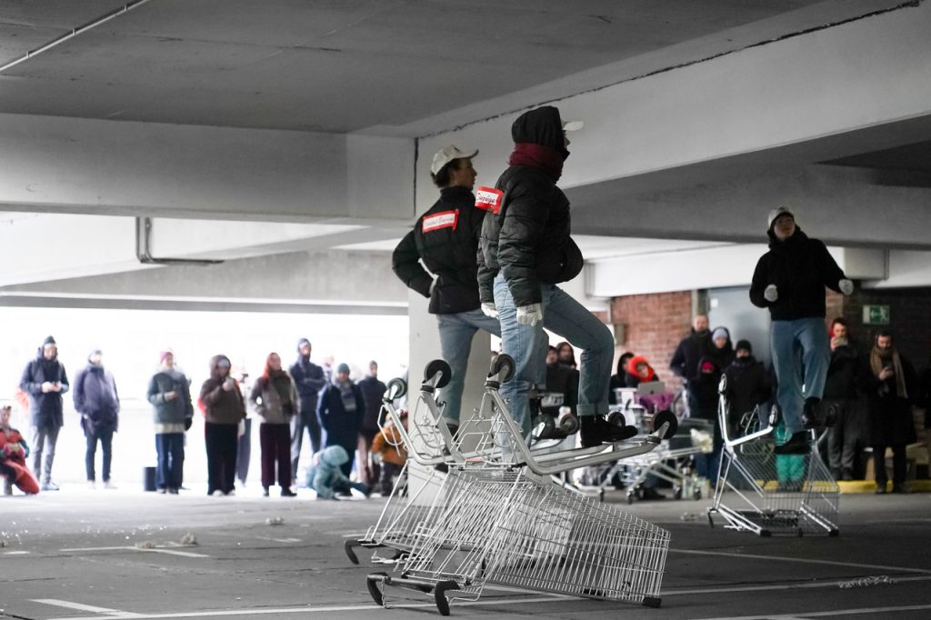 Zwei Menschen mit schwarzen Jacken stehen auf Einkaufswägen