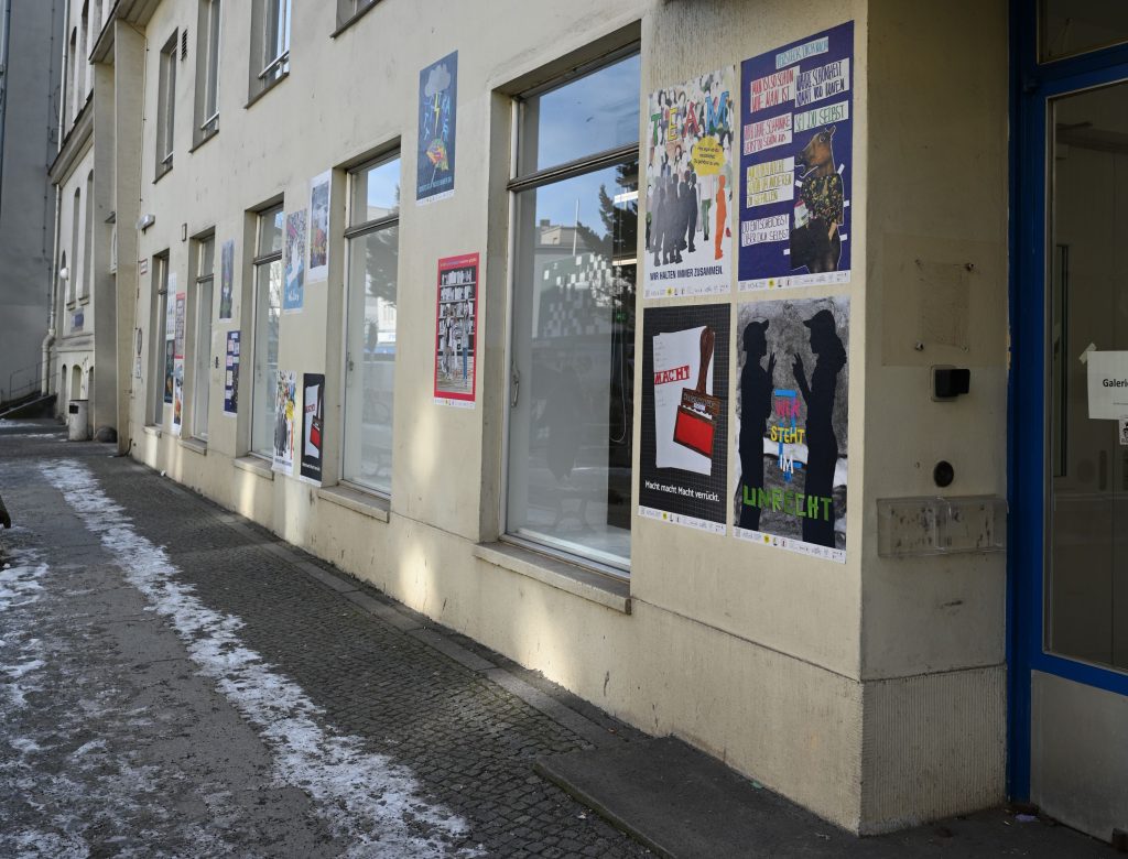 Häuserfassade mit großen Fenstern und bunten Plakaten
