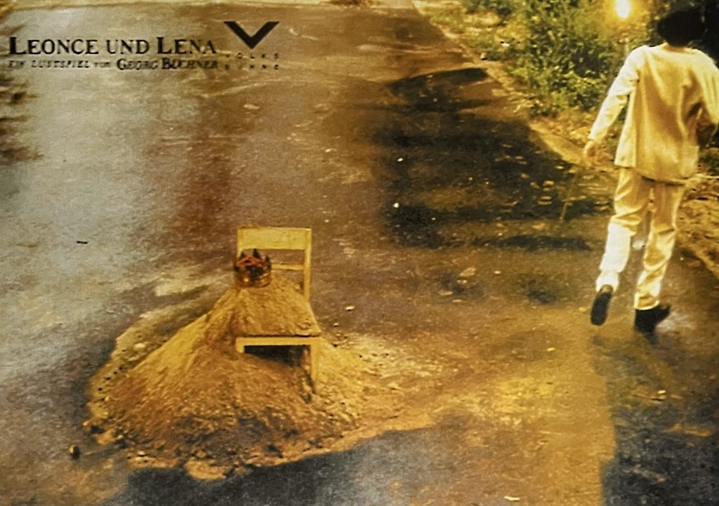 Straße mit Sandberg, daneben ein Mann in weiß von hinten